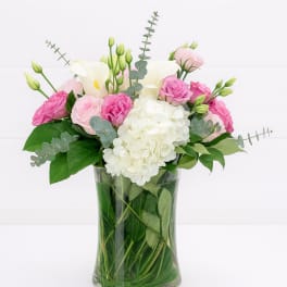 Pink and white flowers arranged in a clear glass vase