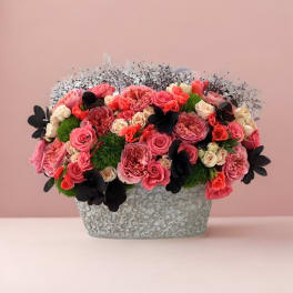 Pink and coral rose arrangement in a textured silver container