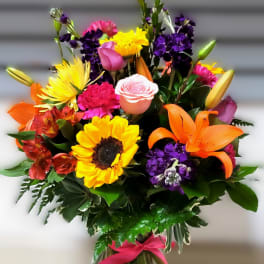 Colorful mixed bouquet in a glass vase with a pink ribbon