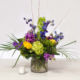 Mixed bouquet in a glass vase with purple, yellow, and green flowers