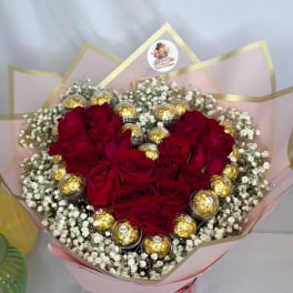 Heart-shaped bouquet of red roses with gold-wrapped chocolates