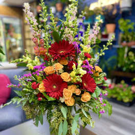 Mixed bouquet with red gerbera daisies and orange roses in a glass vase