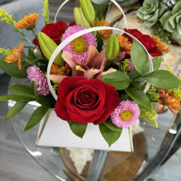 Red roses and pink daisies in a white handled box