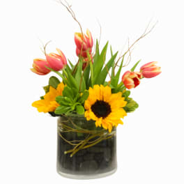 Tulips and sunflowers arranged in a glass vase