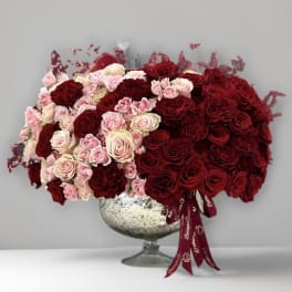 Large arrangement of red and blush roses in a silver pedestal vase
