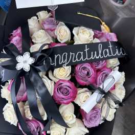 Bouquet of pink, lavender, and white roses with a congratulatory ribbon