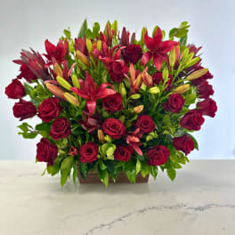 Red roses and lilies arranged in a low rectangular container