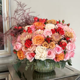 Large bouquet of pink, red, and peach roses in a glass vase