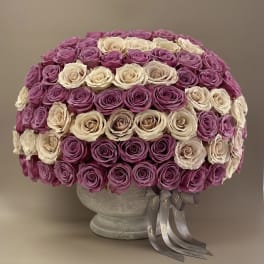 Round arrangement of pink and cream roses in a gray vase