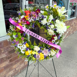 Large floral wreath on an easel with a pink ribbon reading "LAUNDRY STAFF"