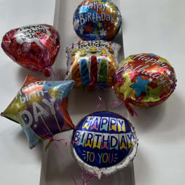 Birthday balloons tied to a teddy bear
