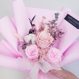 Pink rose bouquet wrapped in pastel paper with a white ribbon