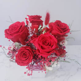 Bouquet of red roses in a white box with pink filler flowers