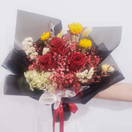 Bouquet of red roses with yellow and white filler flowers wrapped in black paper