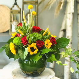 Red roses and yellow flowers arranged in a dark glass vase