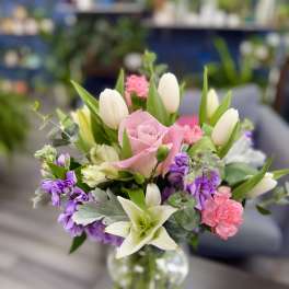Pink roses and white tulips in a clear glass vase