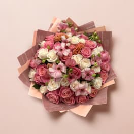 Pink and white rose bouquet with small pink flowers in decorative wrap