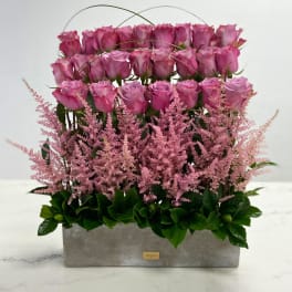 Pink roses arranged in a rectangular gray box with arching wire accents