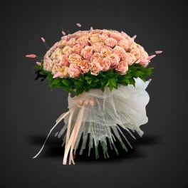 Large bouquet of peach-pink roses with white tulle wrapping and ribbon