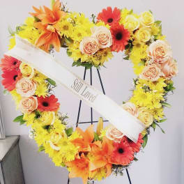 Heart-shaped floral wreath with yellow, orange, red, and peach flowers