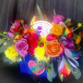 Colorful bouquet of roses and daisies in a gift bag with rainbow ribbon
