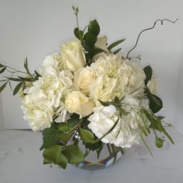 White roses and hydrangeas in a clear glass vase