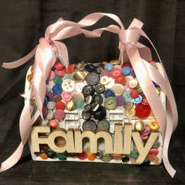 Decorative basket filled with colorful buttons and a pink ribbon bow