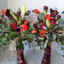 Two floral arrangements in burgundy boots with red and orange flowers