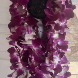 Purple orchid lei draped over a dark doorknob