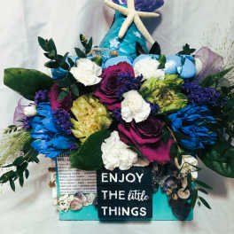 Colorful floral arrangement with a starfish topper and a sign reading "ENJOY THE little THINGS"