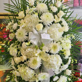 Large white funeral wreath with roses, chrysanthemums, and lilies