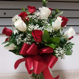 Red and white roses in a glass vase with a red ribbon