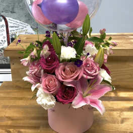 Pink and purple flower arrangement with a clear birthday balloon