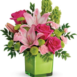 Pink lilies and roses in a green square vase