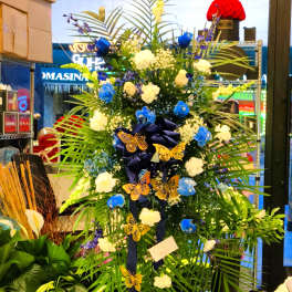 Tall floral standing spray with blue and white flowers and butterfly accents