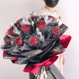 Bouquet of red roses wrapped in black and pink paper