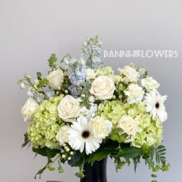 White roses and green hydrangeas in a dark blue vase