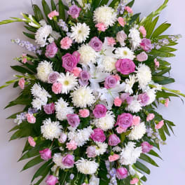 Large standing spray of pink and white flowers with palm leaves