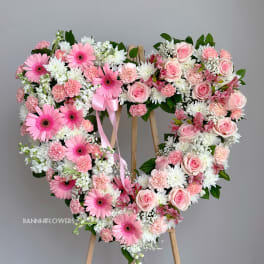 Heart-shaped floral wreath with pink roses and gerbera daisies on an easel