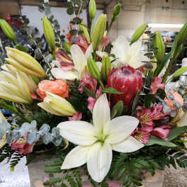 Mixed bouquet with white lilies, pink flowers, and eucalyptus in a wooden box