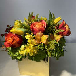 Orange and red roses with yellow flowers in a gold vase
