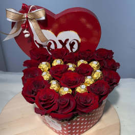 Heart-shaped box of red roses with gold-wrapped chocolates and a ribbon bow