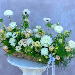 Large white floral arrangement in a rustic bark container