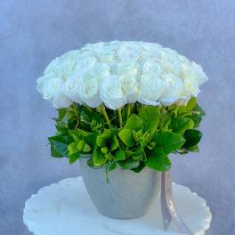 Round bouquet of white roses in a speckled gray vase