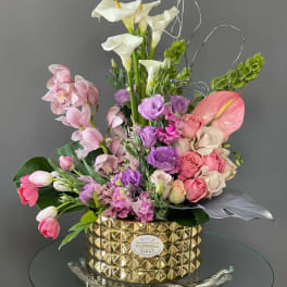 Mixed bouquet with white calla lilies, pink orchids, and roses in a gold vase