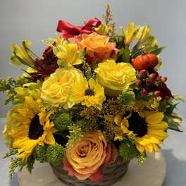 Basket arrangement with yellow roses, sunflowers, and orange blooms