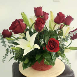 Red roses and white lilies in a red basket arrangement