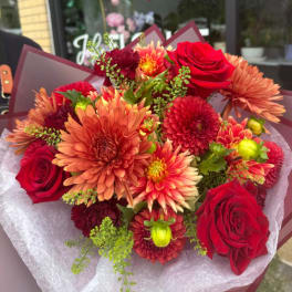 Bouquet of red roses and orange chrysanthemums wrapped in burgundy paper