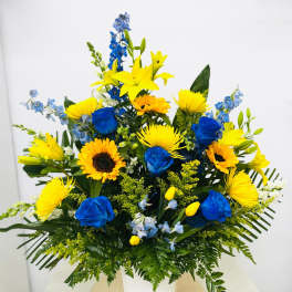 Blue and yellow mixed bouquet in a white container