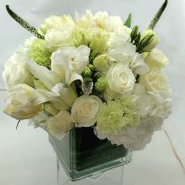 White and pale green bouquet in a clear square vase